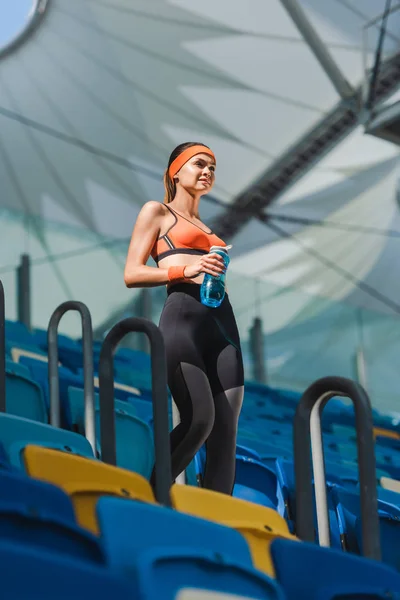 Vista inferior de la hermosa mujer joven caminando por las escaleras en el estadio de deportes - foto de stock