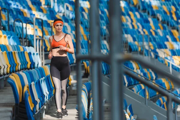 Bella giovane donna a piedi da tribune allo stadio sportivo — Foto stock