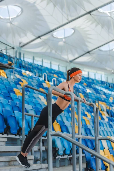 Attractive young woman doing push ups on tribunes at sports stadium — Stock Photo