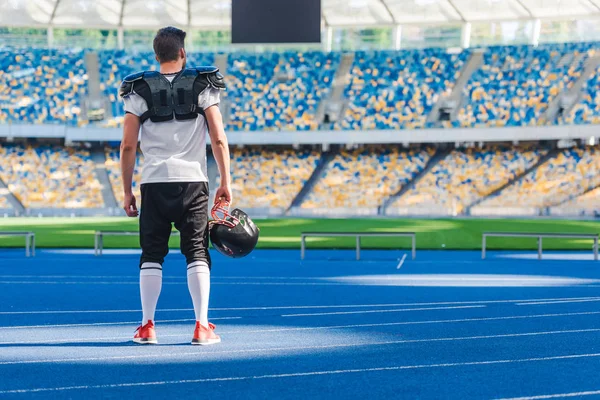 Вид сзади американского футболиста, стоящего в одиночестве на спортивном стадионе — стоковое фото