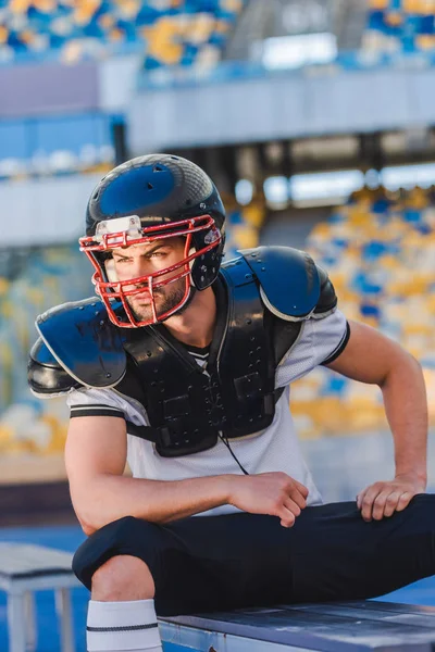 Handsome young american football player sitting at sports stadium — Stock Photo