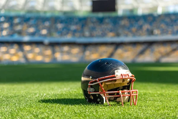 Крупный план американского футбольного шлема, лежащего на зеленой траве стадиона — стоковое фото