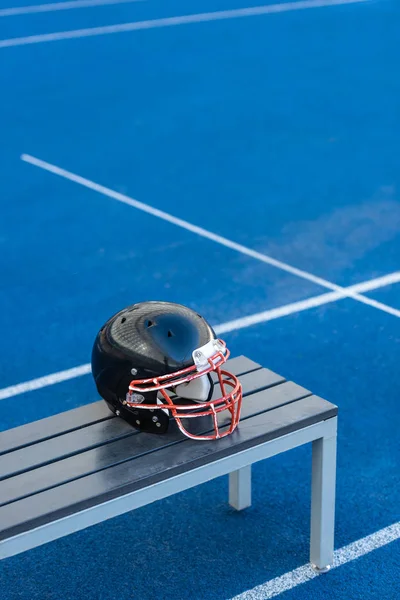 Американский футбольный шлем лежит на скамейке на стадионе — стоковое фото