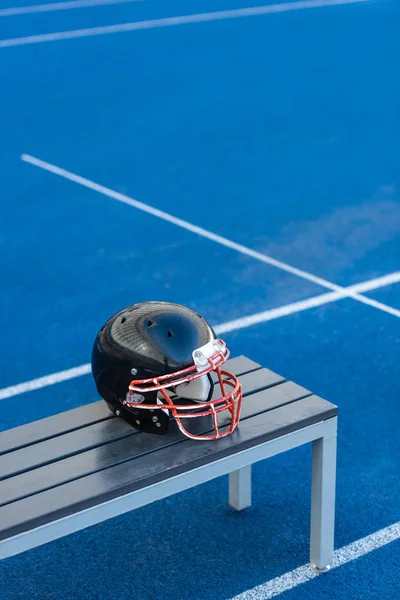 Casco de fútbol americano acostado en el banco en el estadio - foto de stock