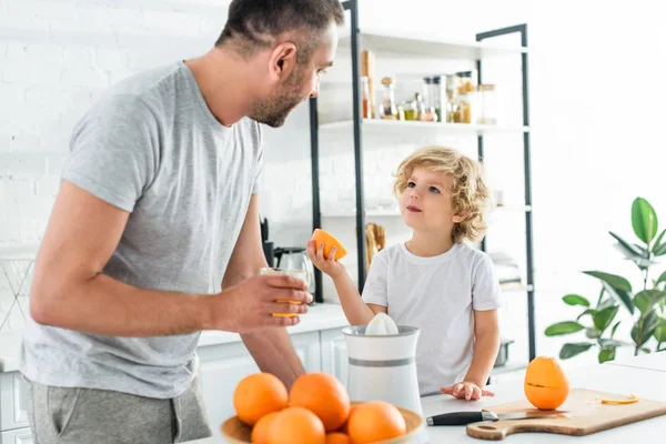 Son and father looking at each other after making fresh orange juice at kithen — Stock Photo