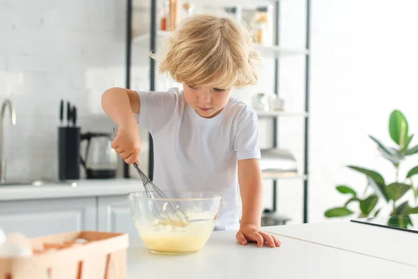Little boy making dough by whisk on table at kitchen — Stock Photo