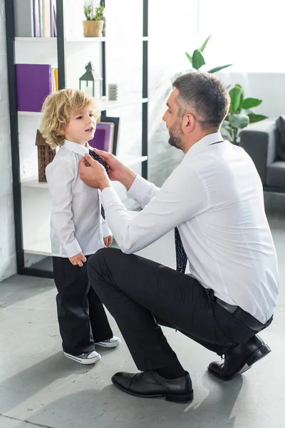 Seitenansicht des Vaters, der seinem kleinen Sohn hilft, Krawatte zu Hause zu binden — Stockfoto