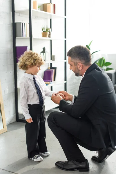 Seitenansicht des Vaters, der Knöpfe am Hemdsärmel des Sohnes befestigt — Stockfoto