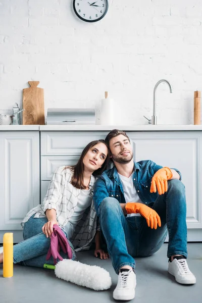 Coppia seduta sul pavimento e appoggiata al bancone della cucina dopo la pulizia in cucina — Foto stock