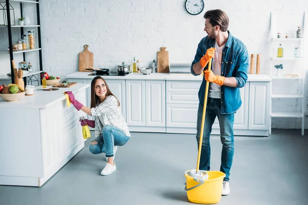 Heureux couple nettoyage cuisine ensemble et regarder l'autre — Photo de stock