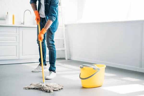 Imagem cortada do homem limpeza chão na cozinha com esfregão — Fotografia de Stock