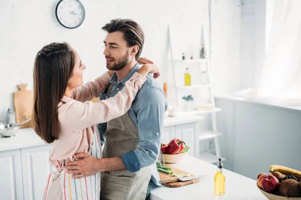Casal abraçando e inclinando-se no balcão da cozinha na cozinha — Fotografia de Stock