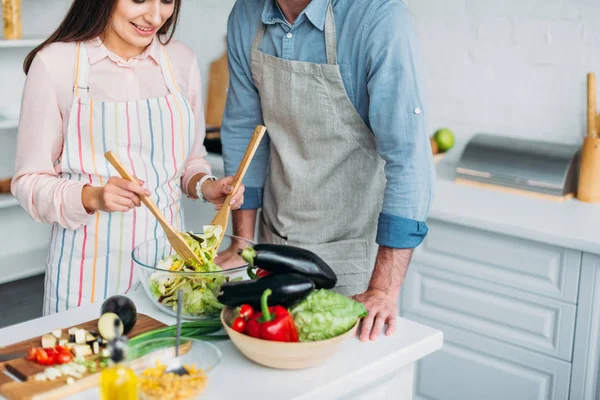 Обрезанный образ подруги приготовления пищи и смешивания салата на кухне — стоковое фото