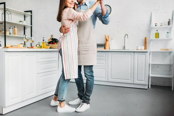 Imagen recortada de pareja abrazando y bailando en la cocina - foto de stock