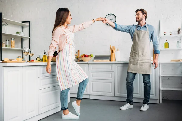 Couple holding hands and dancing in kitchen — Stock Photo