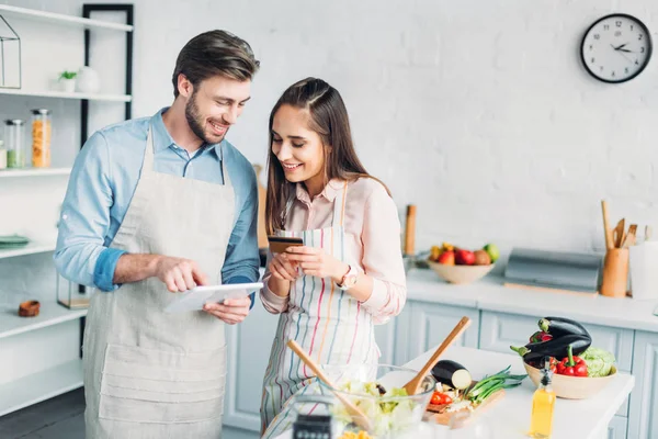 Coppia felice shopping online con tablet e carta di credito in cucina — Foto stock