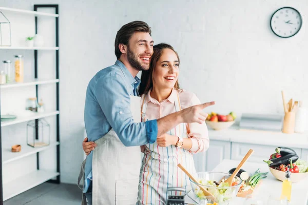 Boyfriend pointing on something to girlfriend during cooking in kitchen — Stock Photo