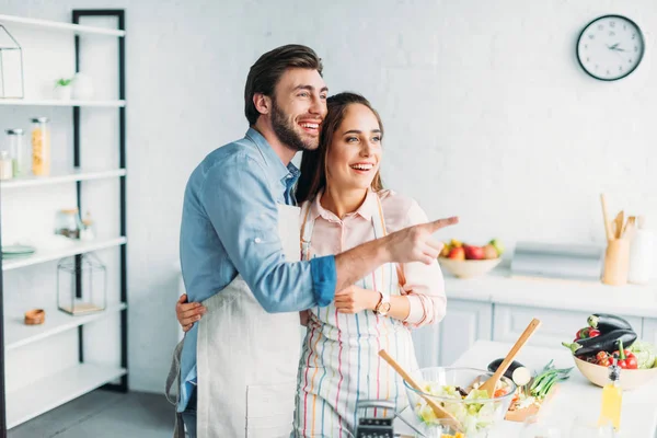 Novio señalando algo a la novia durante la cocina en la cocina - foto de stock