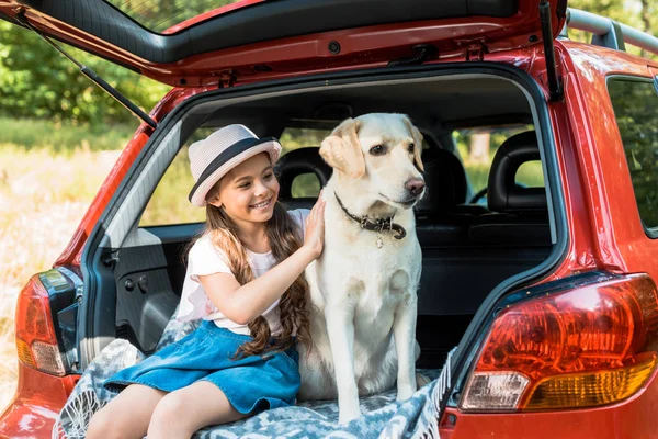 Adorable enfant étreignant chien sur le coffre de voiture — Photo de stock