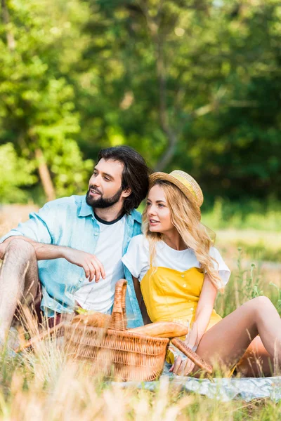 Пара сидить на ковдрі на пікніку і дивиться в сторону — стокове фото