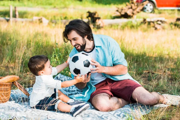 Handsome father and toddler son playing with football ball at picnic — Stock Photo