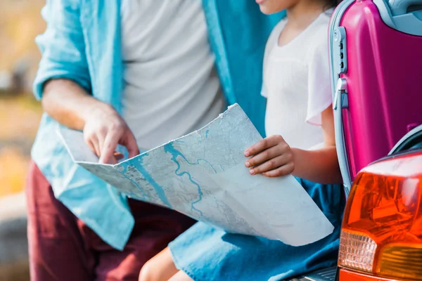 Image recadrée de père et fille regardant la carte au coffre de la voiture — Photo de stock