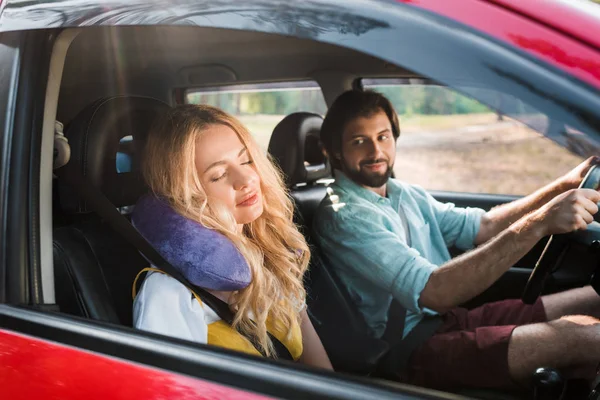 Girlfriend sleeping in car with traveling pillow, boyfriend driving car — Stock Photo