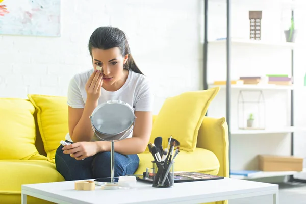 Portrait of young attractive woman doing makeup on sofa at home — Stock Photo