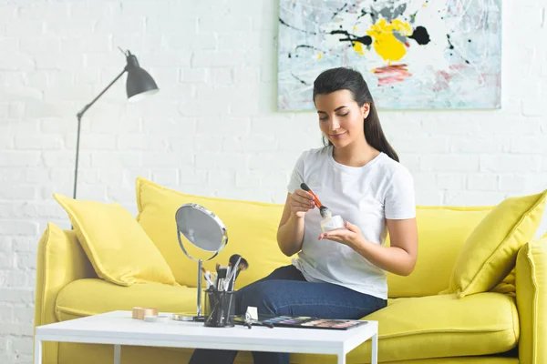 Portrait of young woman with face powder in hands doing makeup at home — Stock Photo