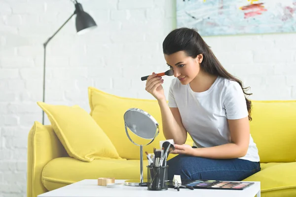 Портрет молодой женщины, наносящей порошок для лица во время макияжа дома — стоковое фото
