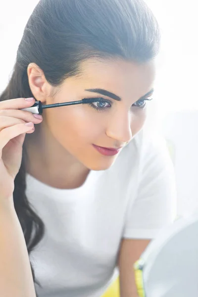 Portrait of attractive young woman applying black mascara on eyelashes — Stock Photo