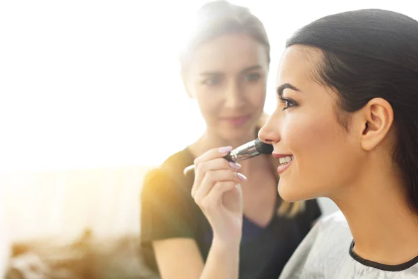 Enfoque selectivo de artista de maquillaje aplicando polvo en la cara de las mujeres con cepillo - foto de stock