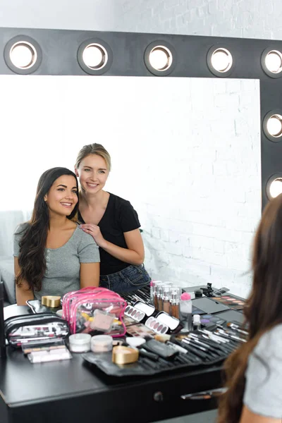 Miroir reflet de belle jeune femme et maquilleuse souriante — Photo de stock