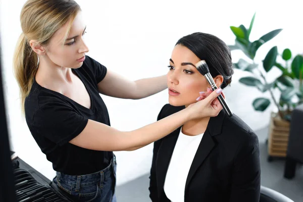 Jovem empresária recebendo maquiagem feita pelo artista de maquiagem — Fotografia de Stock