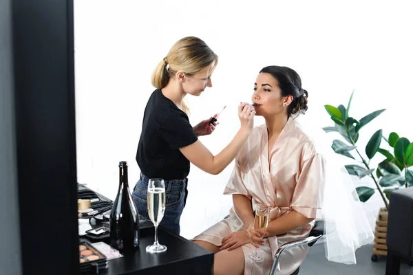 Side view of makeup artist applying lipstick on brides lips — Stock Photo