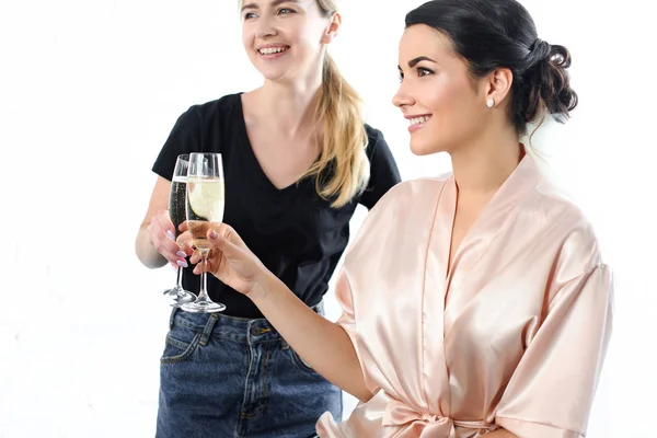 Maquilleur souriant et mariée cliquetis verres de champagne isolé sur blanc — Photo de stock