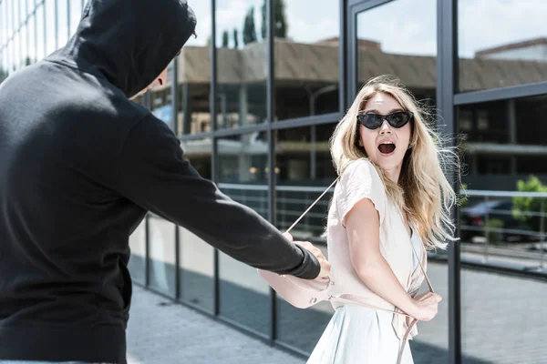 Male criminal robber stealing womans bag on street — Stock Photo