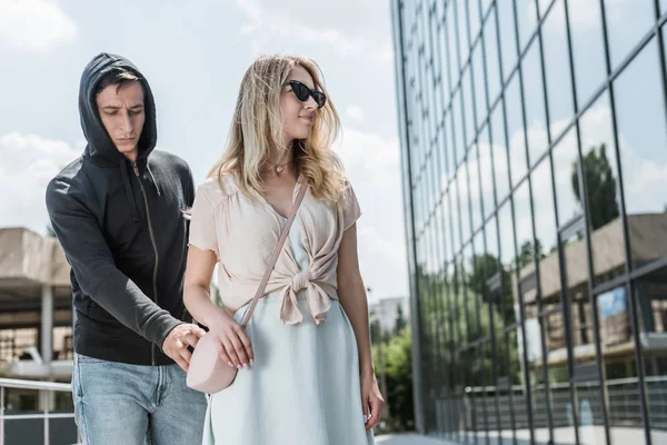 Criminal man pickpocketing from womans bag on street — Stock Photo