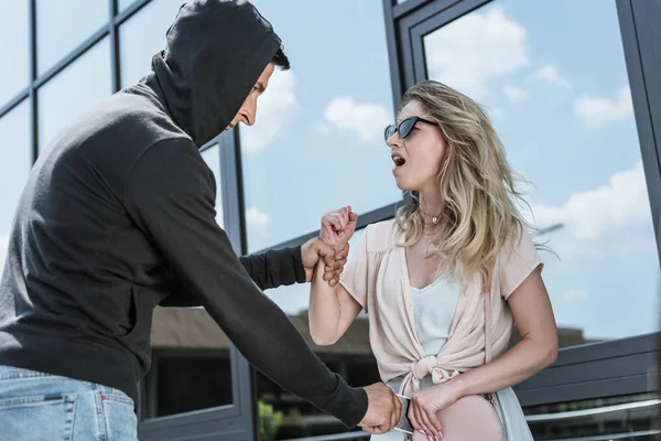 Aggressive male criminal robber stealing smartphone from bag of scared yelling girl — Stock Photo