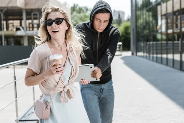 Robo masculino robar mujeres portátil en la calle - foto de stock