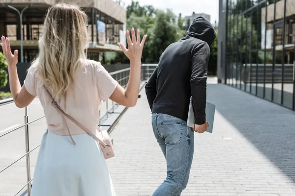 Back view of male robbery stealing laptop on street — Stock Photo