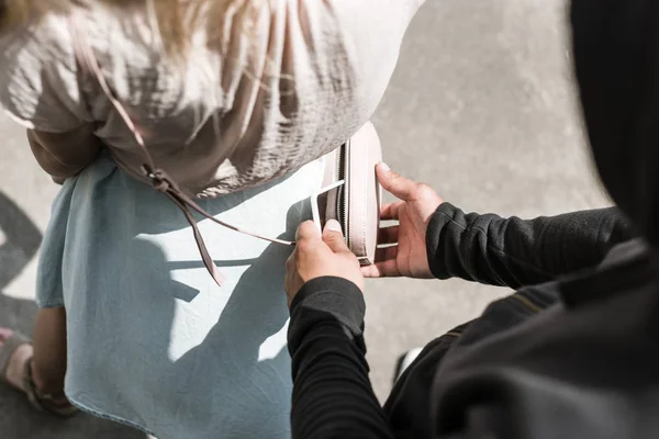 Cropped view of robbery pickpocketing smartphone from womans bag — Stock Photo