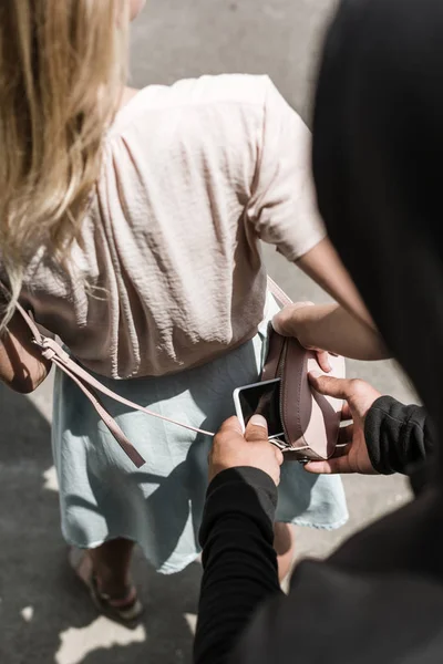 Visão cortada do homem pickpocketing smartphone de saco de mulheres — Fotografia de Stock