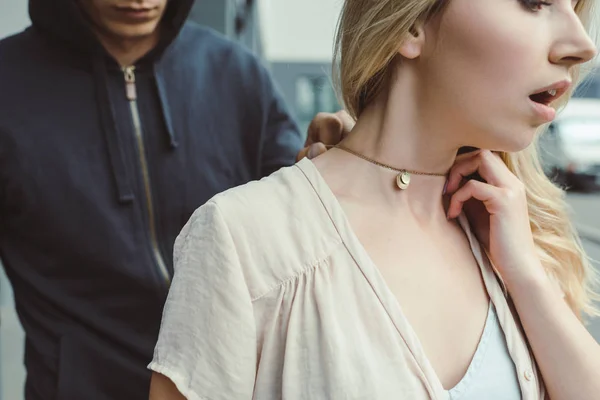 Cropped view of robber attacking woman and stealing pendant on street — Stock Photo