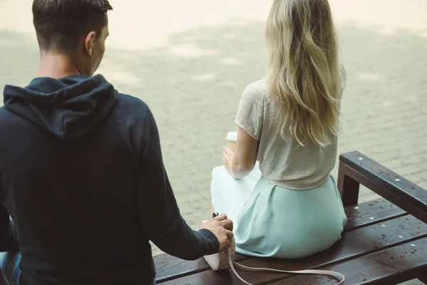 Back view of man pickpocketing wallet from womans bag on bench in park — Stock Photo