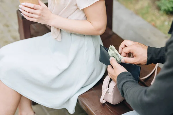 Cropped view of man pickpocketing money from wallet of woman in park — Stock Photo