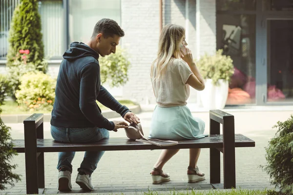 Vista posteriore della rapina borseggiando portafoglio da borsa di donna parlando su smartphone e guardando lontano nel parco — Foto stock