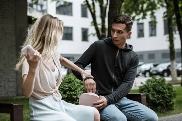 Femme attrapé homme qui pickpocketing son portefeuille de sac sur banc dans le parc — Photo de stock