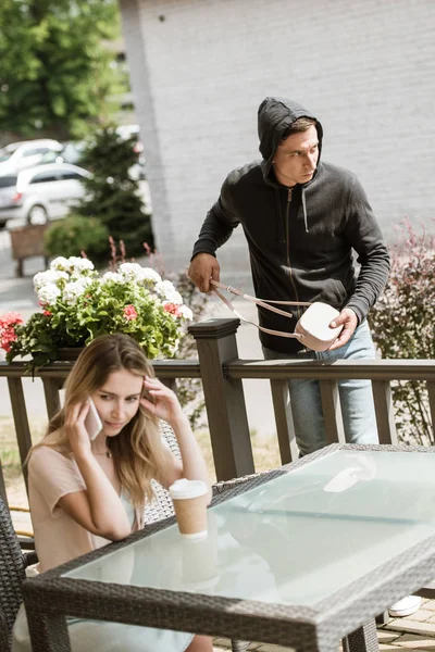 Vol sac de vol de table sur la terrasse du restaurant tandis que la femme parle sur smartphone — Photo de stock