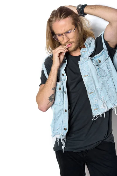 Handsome young man in denim vest smoking roll up cigarette on white — Stock Photo